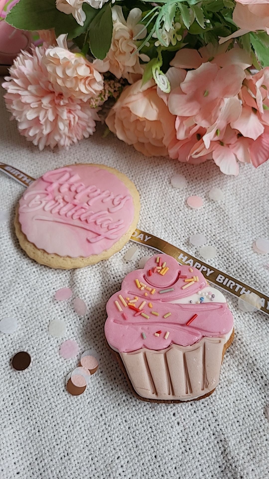 Two pink birthday biscuits, a round Happy Birthday biscuit and cupcake-shaped biscuit