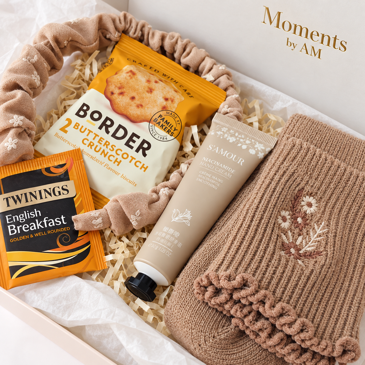 Close-up of embroidered socks, ruffled floral headband, hand cream, Border biscuits and Twinings tea