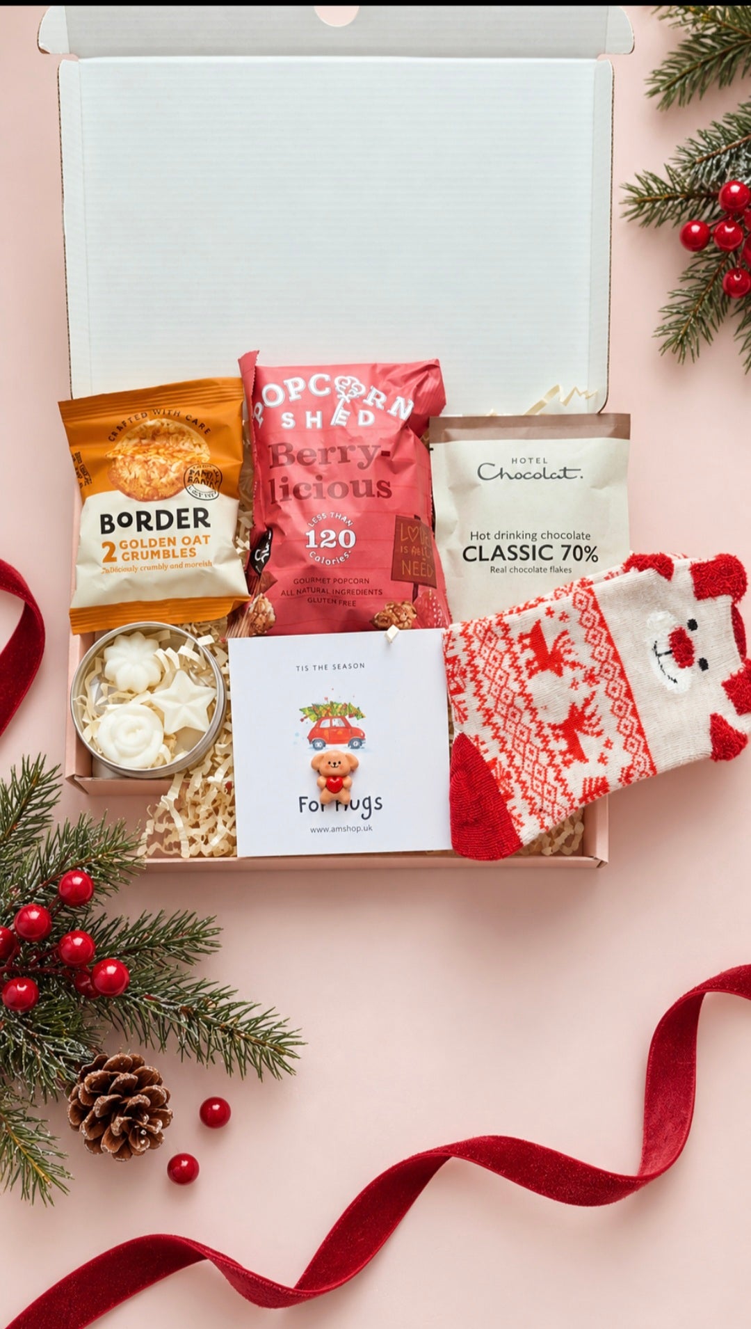 Festive gift box showing all included treats, red and cream socks, Mocha by the Fire wax melts and teddy pocket hug.