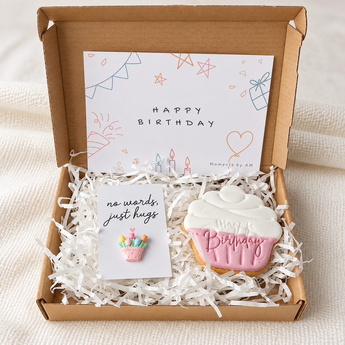 Birthday hug gift box with pink cupcake-shaped biscuit, flower-basket keepsake and birthday card