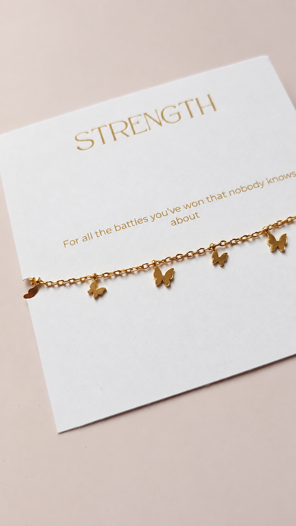 Close-up of the gold butterfly charms and Strength sentiment card
